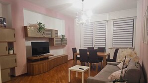 Una sala de estar moderna con televisor, sofá, mesa de comedor y sillas.