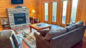 A cozy living room with a stone fireplace, leather sofa, and a coffee table. - Harvest Moon - Cabin In The Smokies (Sevierville)