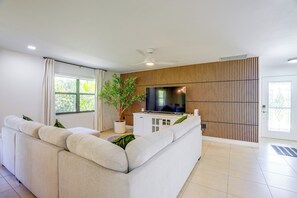 A modern living room with a sectional sofa, a flat-screen TV, a potted plant, and a sliding wooden door.