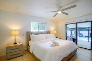 A hotel room with a bed, two bedside lamps, a ceiling fan, a window with blinds, and a view of a pool area. - Renovated Naples Oasis w/ Pool: 2 Mi to Beach (Naples)