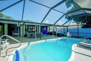 Une piscine avec un patio couvert, des sièges extérieurs et une vue sur le ciel.