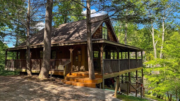 Eine rustikale Holzhütte mit einer Holzterrasse, einer Veranda und einer Treppe zum Eingang.