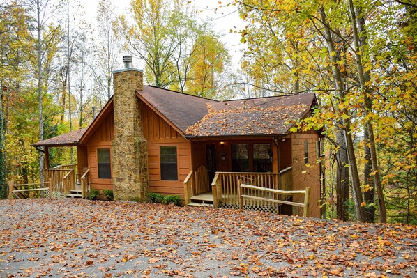 A cabin with a stone chimney, wooden exterior, and a porch with a railing. - Weeks Worth - Cabin in the Smokies (Sevierville)