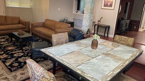 A spacious living room with a large marble table, patterned sofas, and a decorative rug.