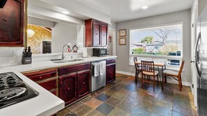 A modern kitchen with a large island, stainless steel appliances, and a view to the outside.