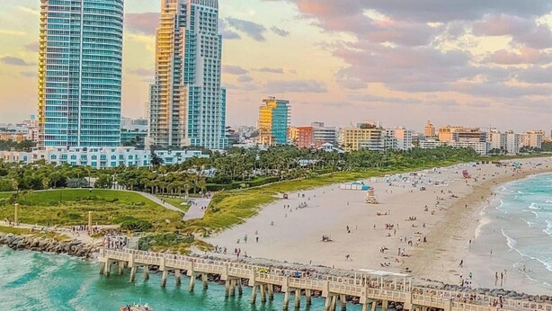 A coastal cityscape with a beach, a pier, and modern high-rise buildings. - Directly on the beach with Free beach lounges.  Best location in South Beach! (Miami Beach)