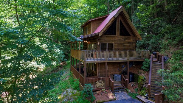 A wooden cabin with a balcony, surrounded by dense forest. - Sweet Serenity - Easy to Access Cabin By A Small Mountain Stream in Wears Valley (Sevierville)