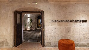 An interior corridor with a rustic stone wall, a wooden door, and a welcome sign. - Hampton by Hilton Arequipa (Arequipa)