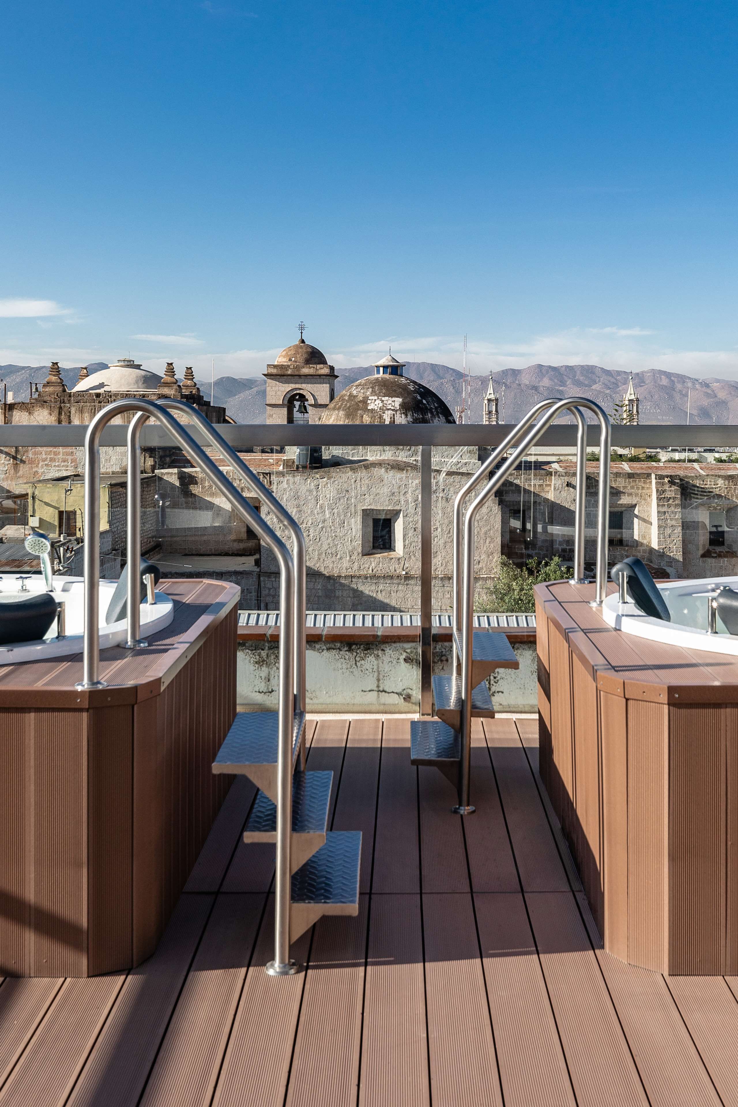 Una terraza de madera con jacuzzis y una escalera de metal.
