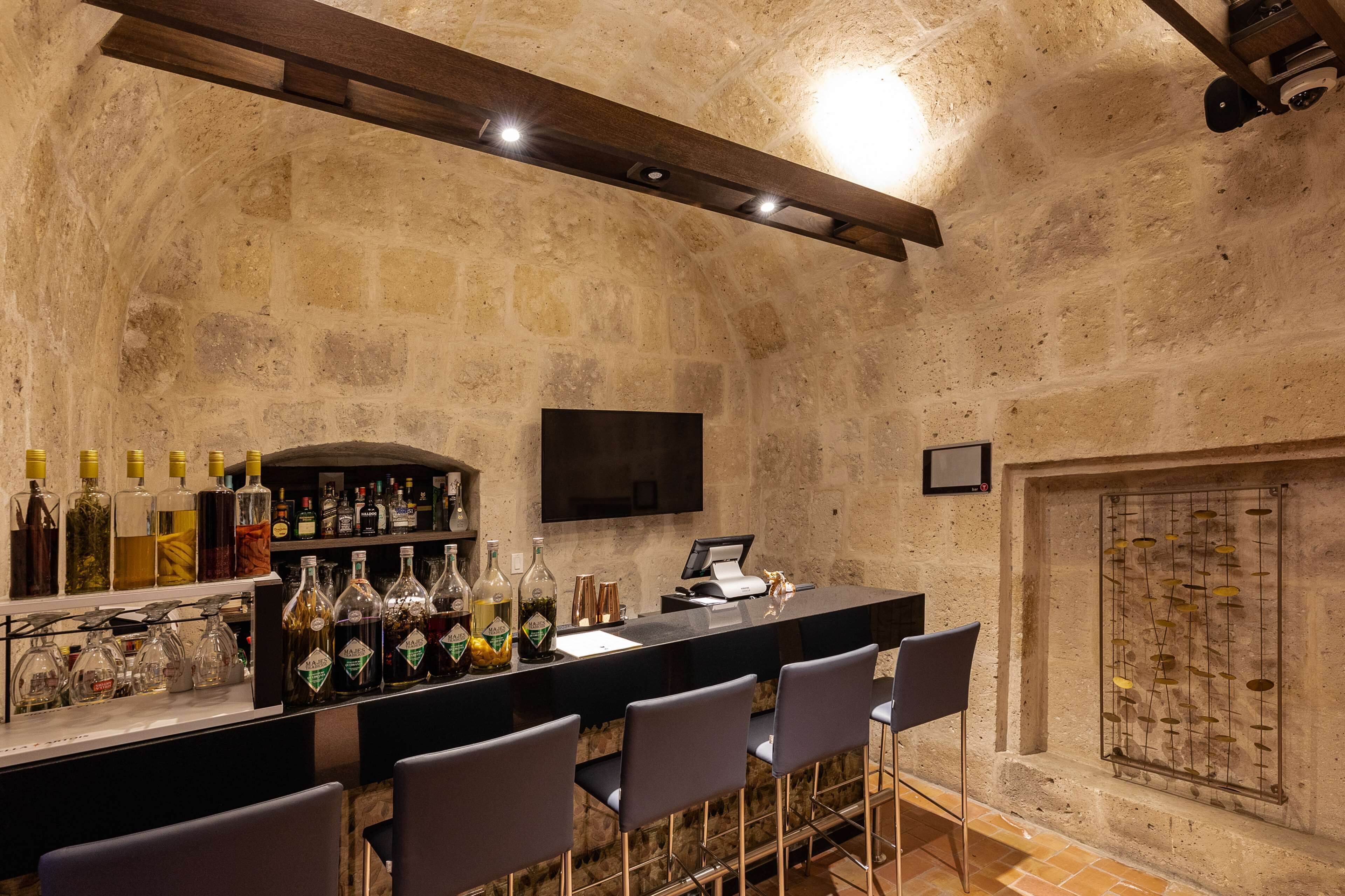 Un área de bar con una pared de piedra, un televisor de pantalla plana y una variedad de botellas.