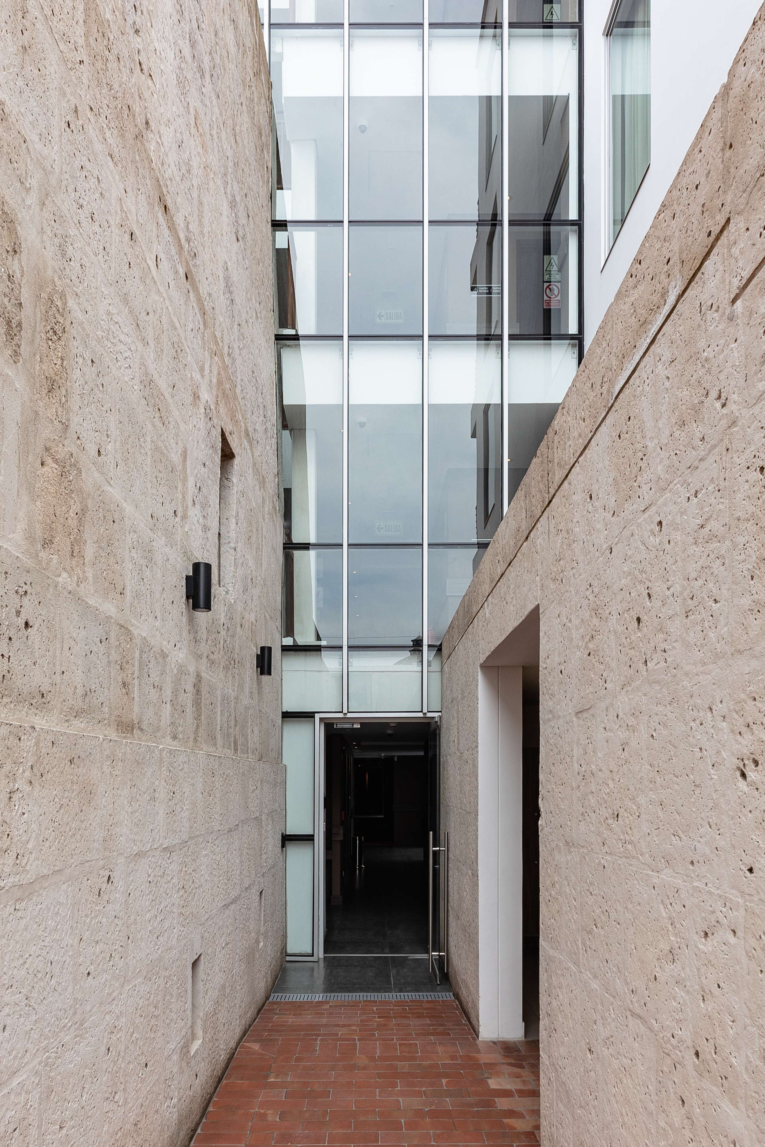 A narrow corridor with a glass facade and a brick floor.