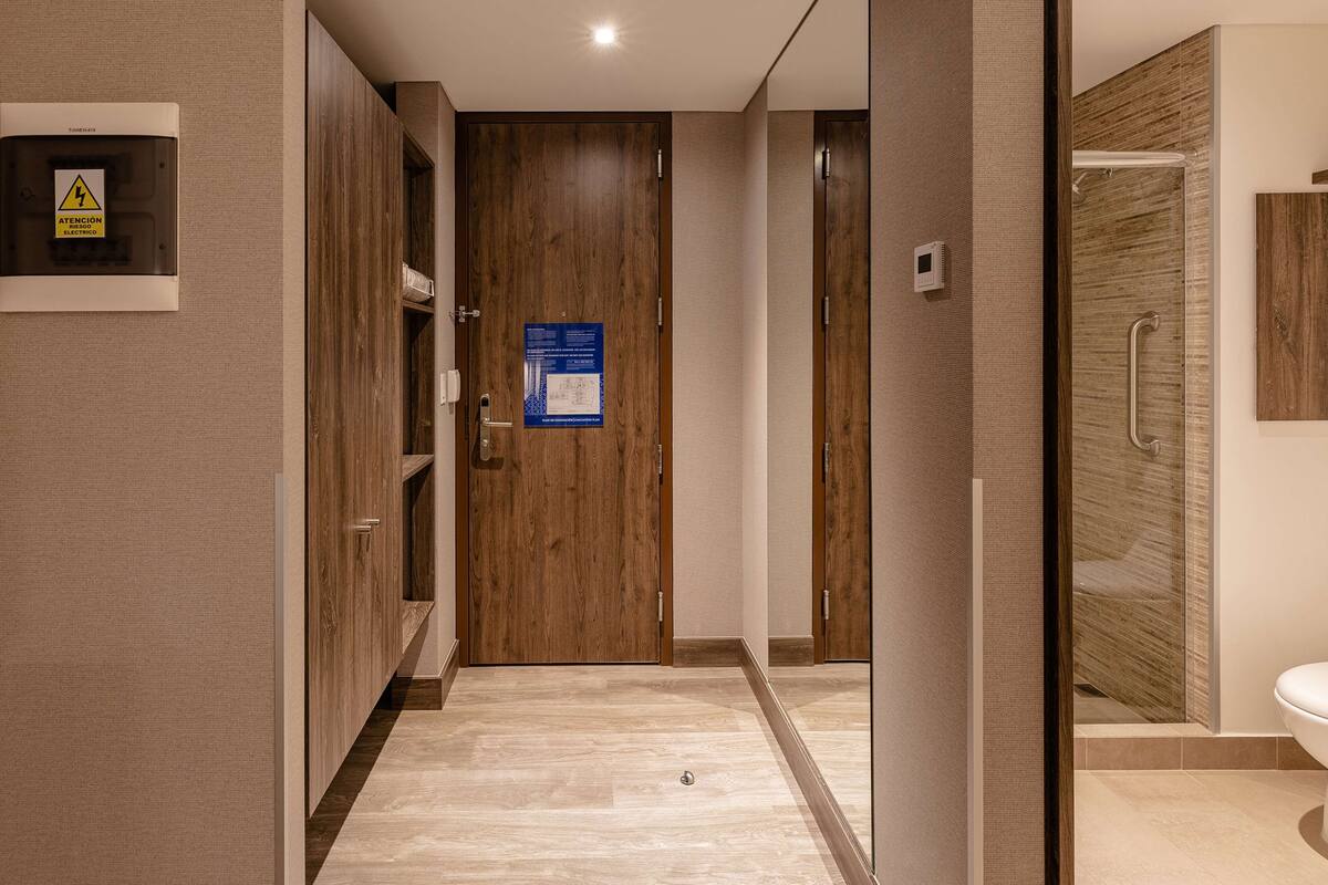 A modern bathroom with a wooden door, a shower area, and a toilet.