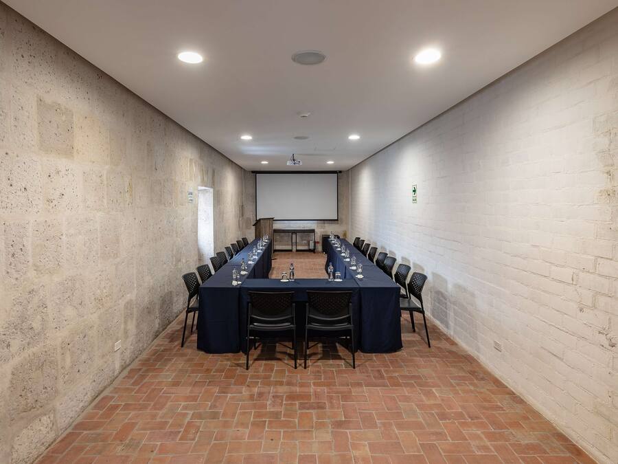 Une salle de conférence équipée d’une longue table, de chaises, d’un écran de projection et d’un tableau blanc.