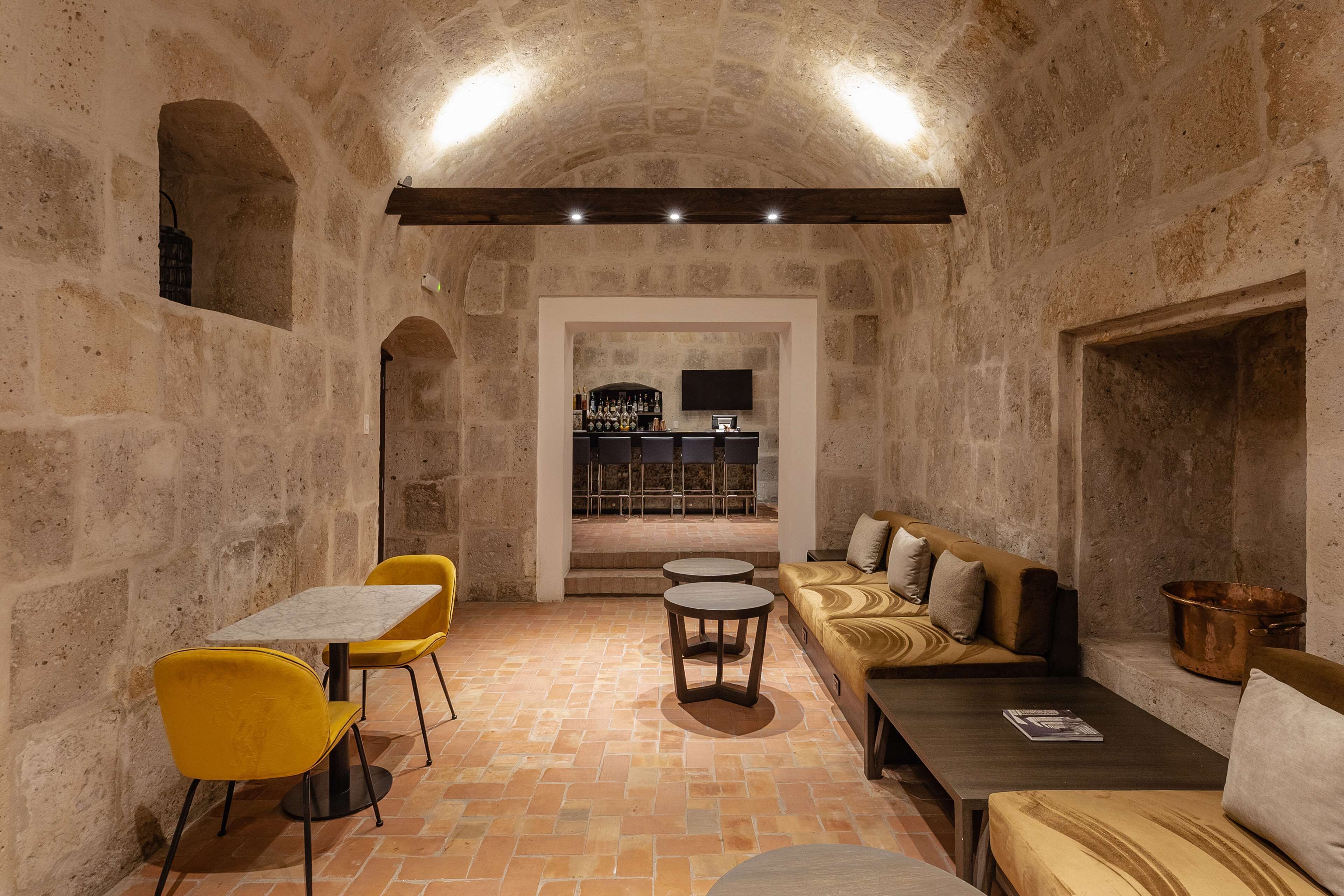 Un interior acogedor con paredes de piedra, una zona de bar y diferentes disposiciones de asientos.