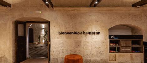 Un interior rústico con pared de piedra, un banco de madera y un letrero que dice 'bienvenido hampton'.