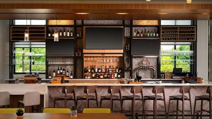A modern bar area with wooden furniture, a bar counter, and wine bottles. - Hilton Garden Inn Grapevine at Silverlake Crossing (Grapevine)