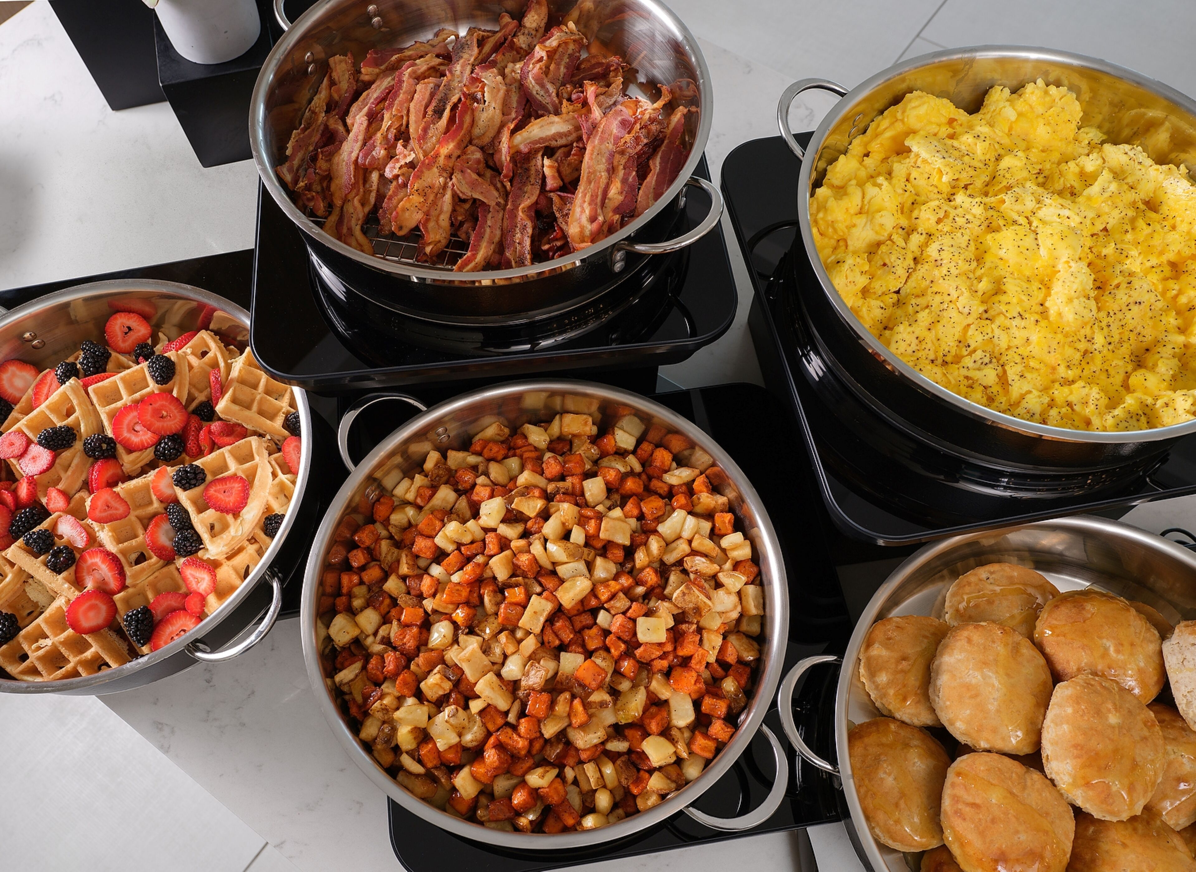 Una cocina con diversos platos, incluyendo gofres, verduras asadas y productos de repostería.