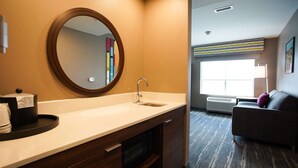 A hotel bathroom with a sink, mirror, and a toilet paper holder.