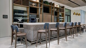 A modern bar area with wooden shelves, bar stools, and a marble countertop. - Hilton Garden Inn Madison Huntsville Airport (Madison)