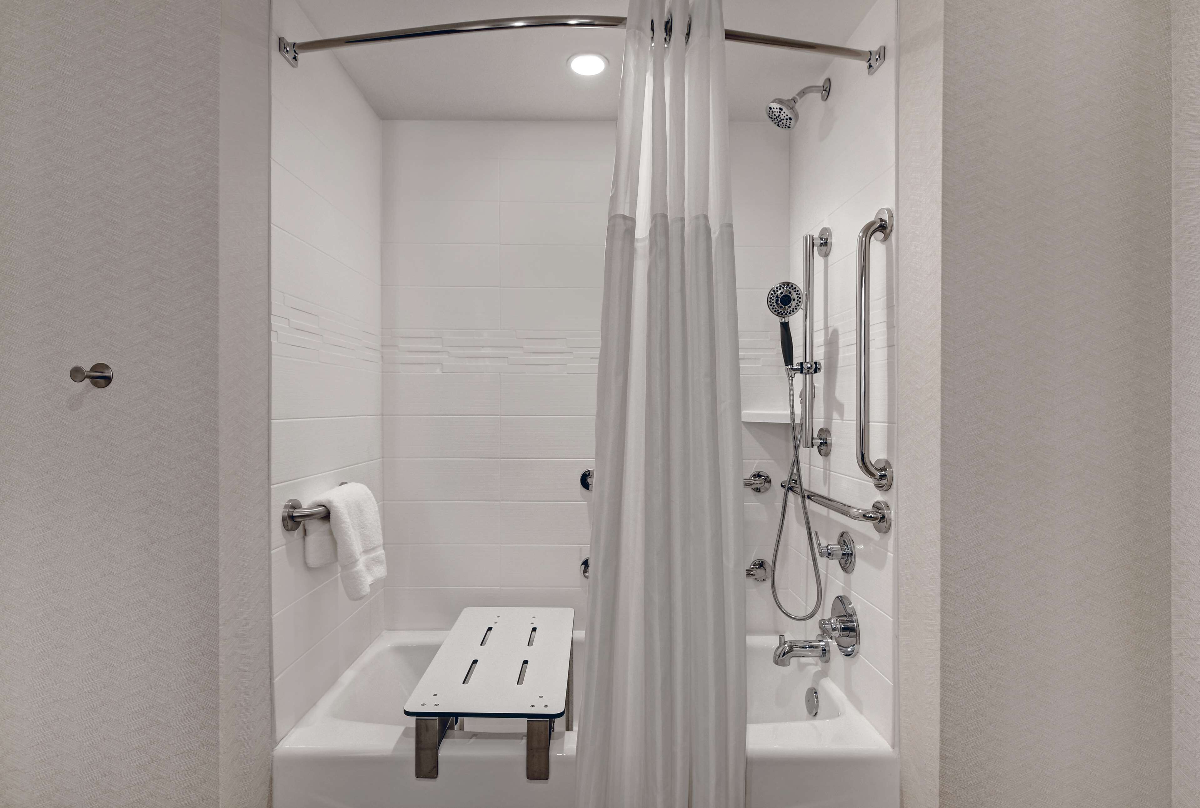 Un baño moderno con ducha, bañera y un pequeño taburete.