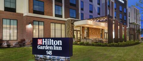 A Hilton Garden Inn building with a sign in front, brick facade, and large windows.