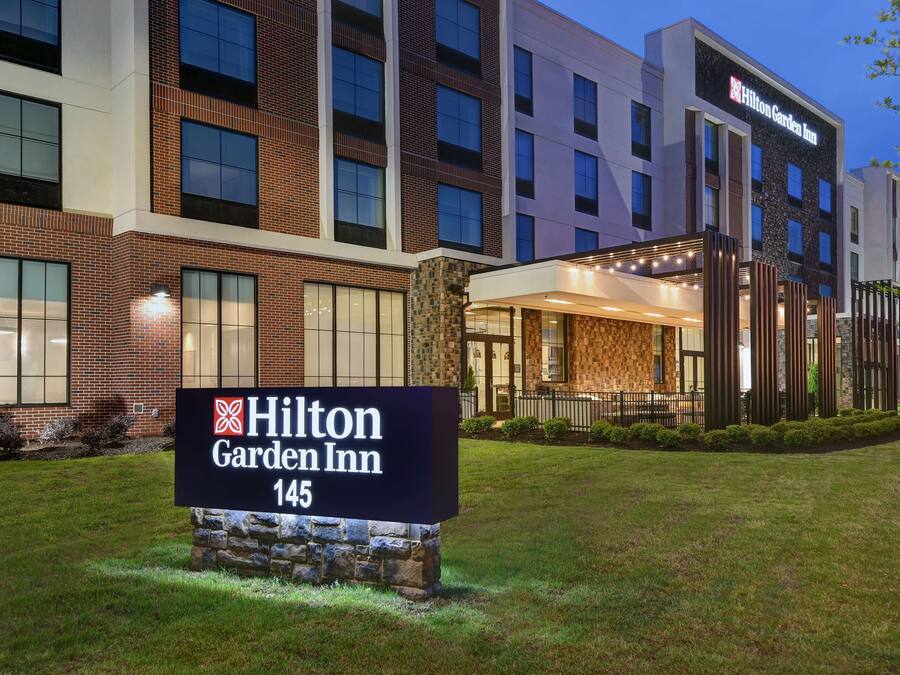 Edificio de Hilton Garden Inn con un cartel al frente, fachada de ladrillo y ventanas amplias.