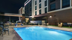 A hotel with a pool area, outdoor seating, and a sign indicating no lifeguard on duty. - Hilton Garden Inn Madison Huntsville Airport (Madison)