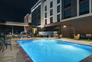 Una piscina al aire libre, sombrillas, sillones reclinables de piscina