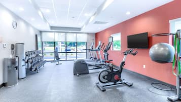 Un gimnasio con máquinas de cardio, mancuernas y una pelota de ejercicio grande.