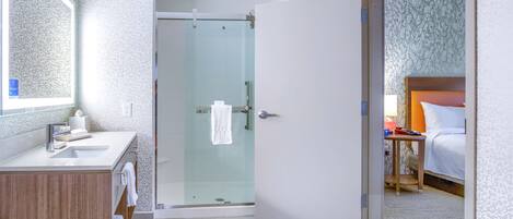 Une salle de bain moderne avec une douche en verre, un meuble-lavabo en bois et un grand miroir.