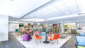 En rummelig lobby med et centralt siddeområde, en receptionsdisk og et køkken i baggrunden.