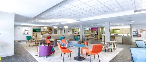 A spacious lobby with a central seating area, a reception desk, and a kitchen visible in the background.