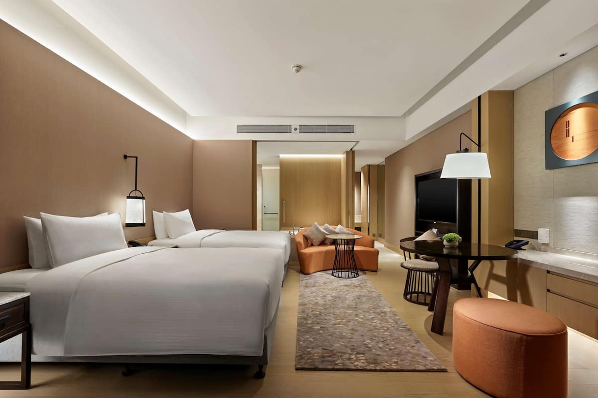 A hotel room with a large bed, a desk, a TV, and a small seating area.