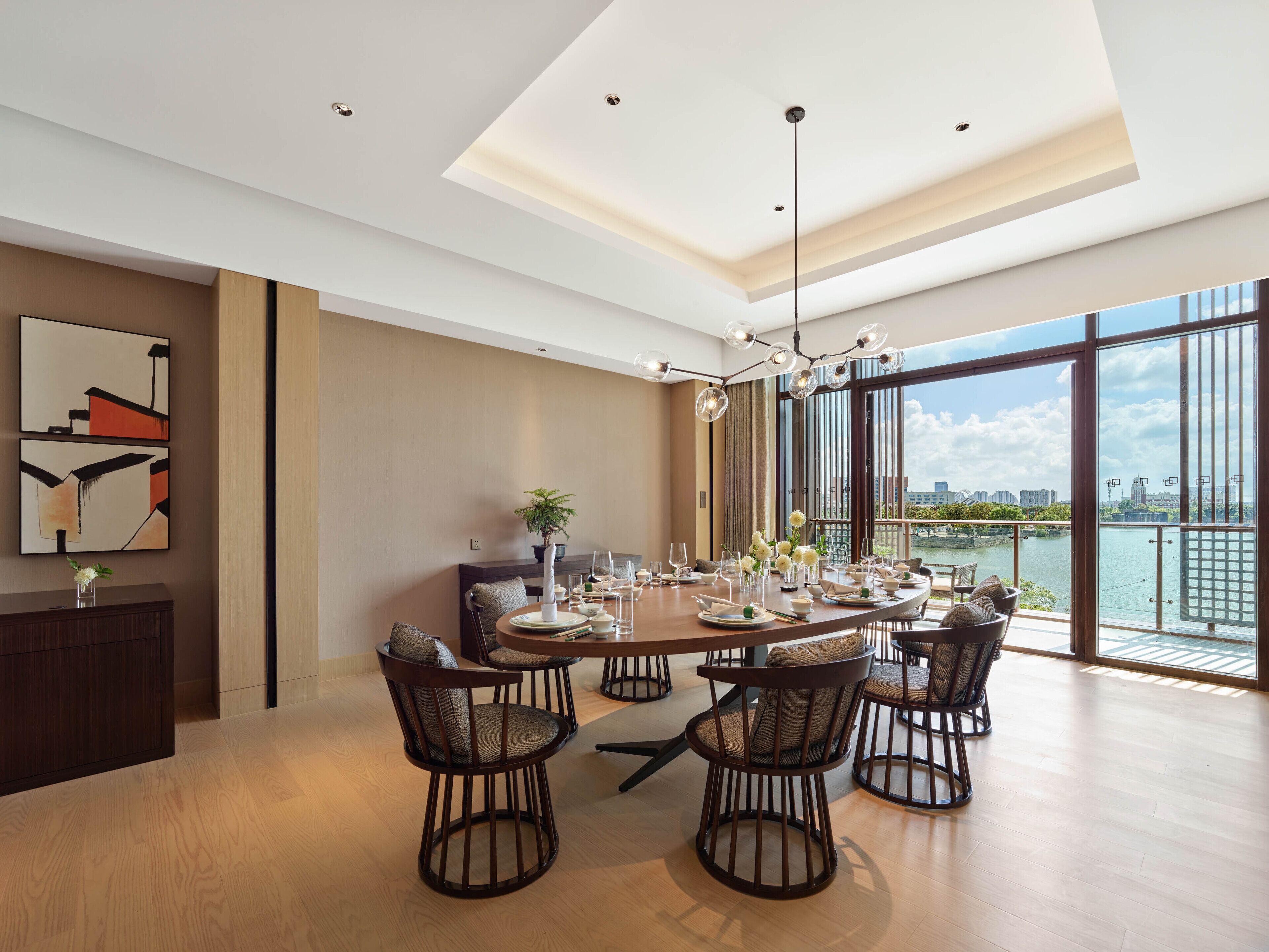 Un espace repas moderne avec une grande table, plusieurs chaises et une vue sur une rivière.