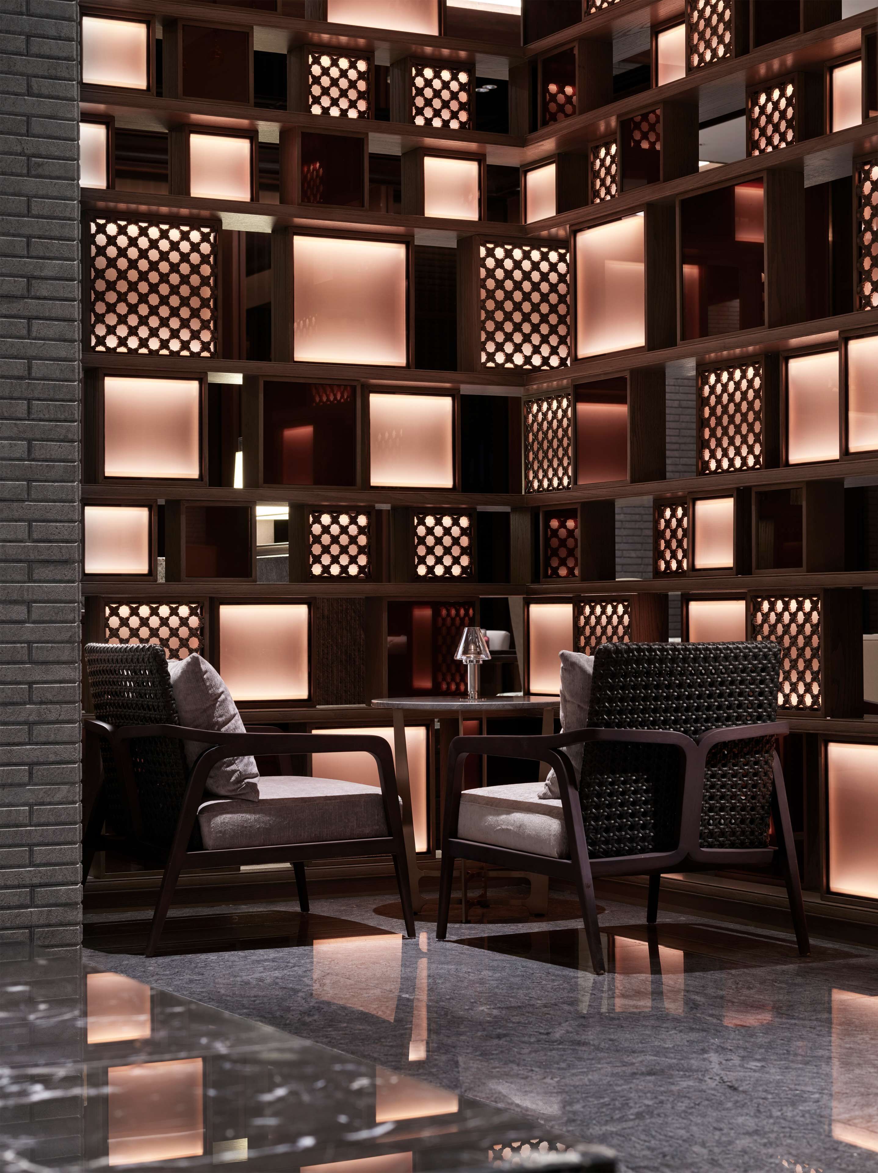 A modern interior with a geometric wall design, two chairs, and a small table.