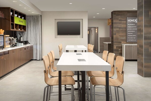 Une chambre d’hôtel moderne dotée d’un coin repas, d’une cuisine et d’un grand téléviseur à écran plat.