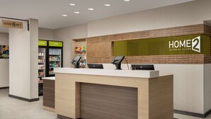 A reception desk with a digital kiosk, a refrigerated display case, and a sign for "HOME 2 Suites by Hilton". - Home2 Suites by Hilton Tampa Westshore Airport, FL (Tampa)