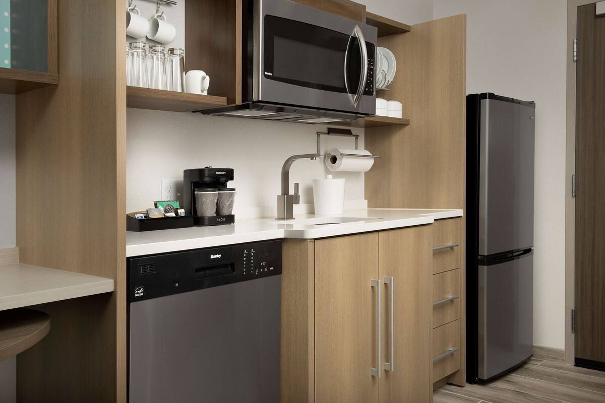 Eine moderne Küche mit eingebautem Geschirrspüler, einer Kaffeemaschine und einem Edelstahl-Kühlschrank.
