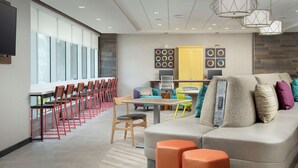 A modern meeting room with a long table, chairs, a sofa, and a television. - Home2 Suites by Hilton Tampa Westshore Airport, FL (Tampa)