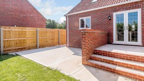 A brick house with a red-tiled roof, a wooden fence, and a small front porch with steps. - Dawson Park 2 - UK12661 (Mablethorpe)