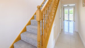 A staircase with wooden balusters and carpeted steps leading to a door with a glass panel. - Dawson Park 2 - UK12661 (Mablethorpe)