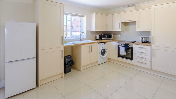 A compact kitchen with a refrigerator, washing machine, microwave, and oven. - Dawson Park 2 - UK12661 (Mablethorpe)