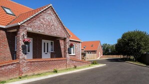 A residential building with a brick facade, red-tiled roof, and a front entrance with a white door. - Dawson Park 2 - UK12661 (Mablethorpe)