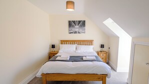 A bedroom with a wooden bed, white bedding, a nightstand with a lamp, and a ceiling light. - Dawson Park 6 - UK12665 (Mablethorpe)