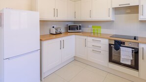 A modern kitchen with white cabinets, a white refrigerator, a microwave, a toaster, and a stove. - Dawson Park 6 - UK12665 (Mablethorpe)