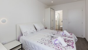 A modern bedroom with a large bed, a bedside table, and a walk-in closet.