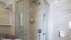 A modern bathroom with a glass-enclosed shower, a white sink, and a toilet.