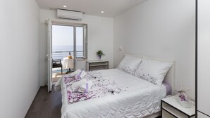 A bedroom with a bed, a nightstand, a window, and an air conditioning unit.