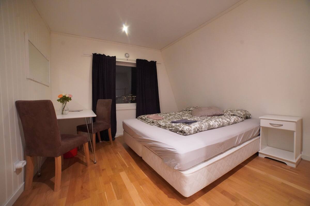A small, clean room with a bed, a desk, and a chair.