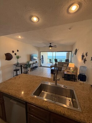 A kitchen with a granite countertop, stainless steel sink, and a ceiling fan.